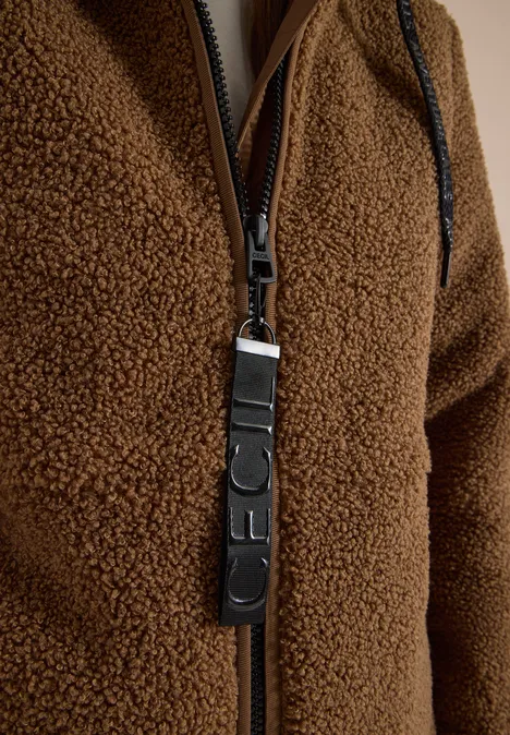 Strukturmix Teddy-Mantel mit Kapuze dark toffee brown Nahaufnahme einer braunen Fleecejacke mit Reißverschluss und Leder-Zipperanhänger.