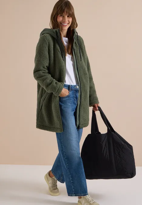 Strukturmix Teddy-Mantel mit Kapuze shadow khaki Frau in grünem Teddy-Mantel, Jeans und Sneakern trägt große schwarze Tasche