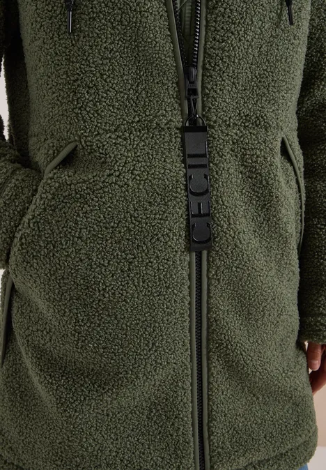 Strukturmix Teddy-Mantel mit Kapuze shadow khaki Nahaufnahme einer grünen Teddy-Fleecejacke mit Reißverschluss und Taschen.