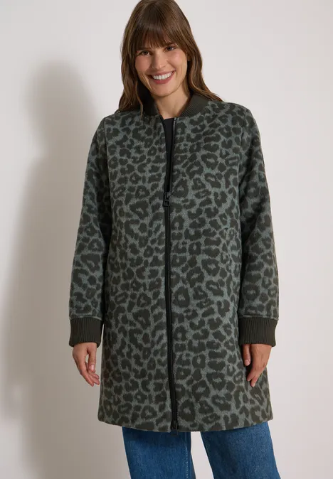 Langer Blouson mit Wollanteil olive night Frau mit grünem, leo-bedrucktem Mantel mit Reißverschluss und schwarzen Bündchen, dazu Jeans.