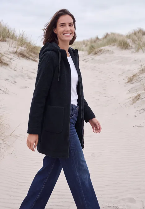 Mantel in angerauter Wolloptik dark navy blue Eine lächelnde Frau in schwarzem Mantel und blauen Jeans spaziert über Dünen am Strand.