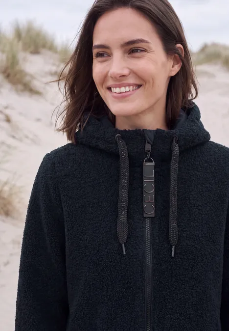 Mantel in angerauter Wolloptik dark navy blue Lächelnde Frau mit schwarzem Fleece-Hoodie an sandigen Dünen.