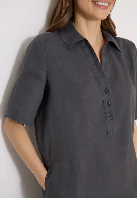 Een vrouw draagt een donkergrijs overhemd met korte mouwen, knoopsluiting en zijzakken.