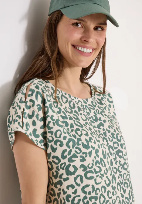 Damen-T-Shirt mit grünem Leopardenmuster, kurzen Ärmeln und rundem Ausschnitt, kombiniert mit grüner Cap.