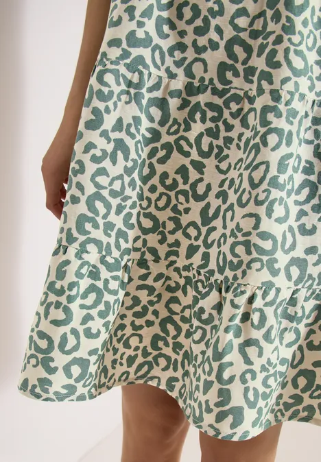 Nahe Aufnahme eines Kleides mit grünem Leopardenmuster und Volant am Saum.