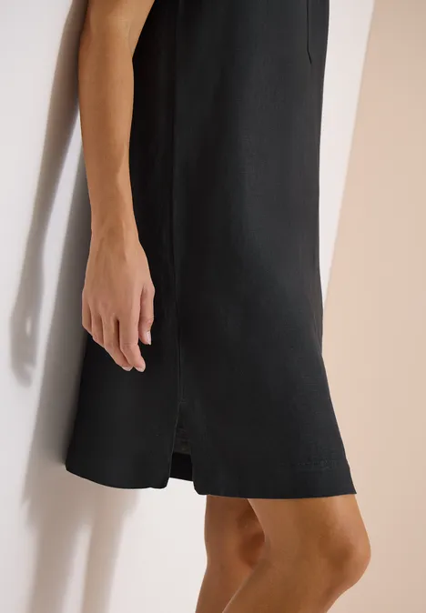 Zwarte mouwloze gebreide jurk tot op de knie met subtiele split onderaan.