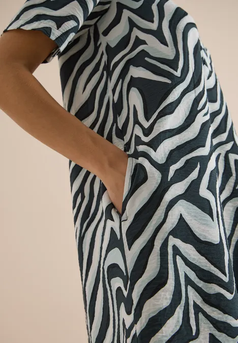Nahaufnahme einer Hand in der Tasche eines Kleides mit Zebra-Print.