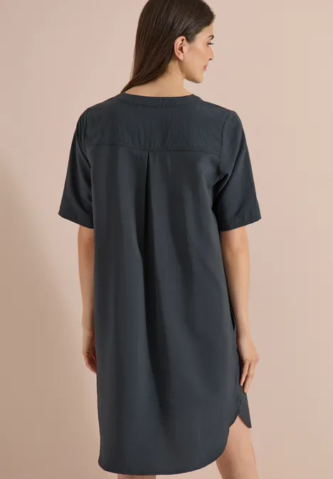 Knielanges Kleid mit Split Neck palm breeze green Frau von hinten in locker sitzendem, knielangem, dunklem Kleid mit kurzen Ärmeln und Rückendetail.