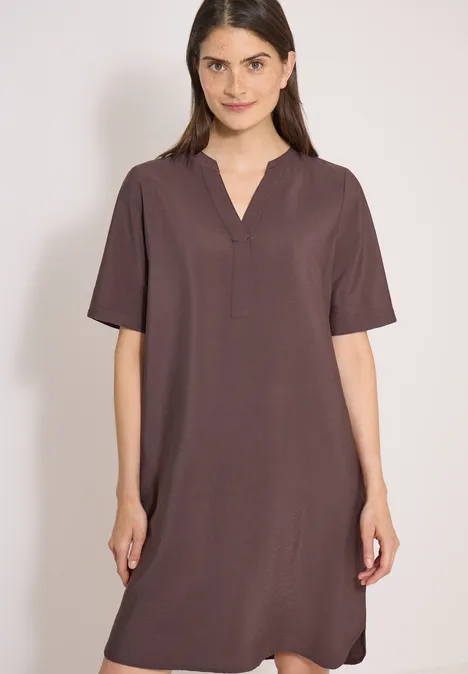 Femme portant une robe courte marron simple à manches courtes et encolure en V, longueur genoux