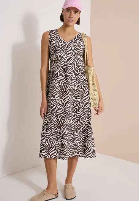 Vrouw draagt mouwloze midi jurk met zebraprint en een gele tas.