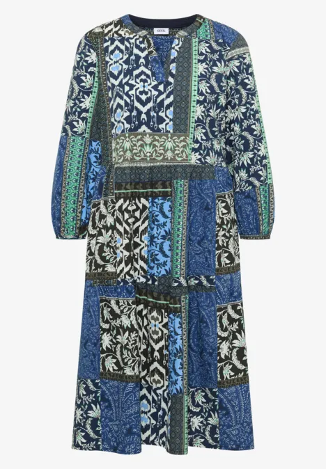 Robe mi-longue à patchwork bleu-vert, manches longues et jupe à volants.