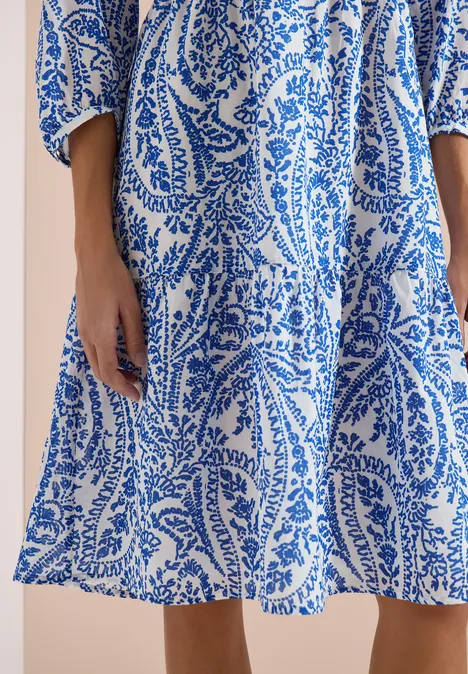Witte zomerse jurk met blauw paisley- en bladmotief, luchtige snit.