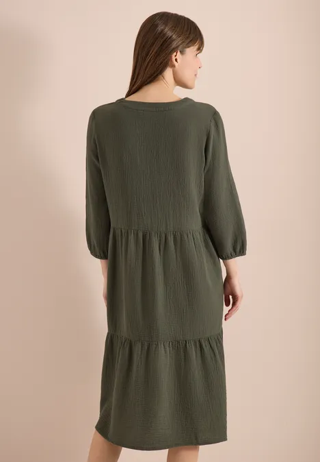 Frau von hinten in locker sitzendem, olivegrünem, stufigem Midi-Kleid mit 3/4-Ärmeln.