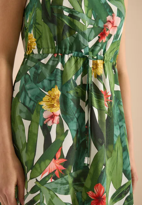 Groene, getailleerde jurk met levendige tropische bloemen- en bladprint, luchtig en zomers.