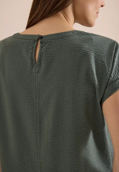 Olivgrünes, strukturiertes T-Shirt mit kurzem Ärmel und kleinem Rückenausschnitt, Ansicht von hinten.