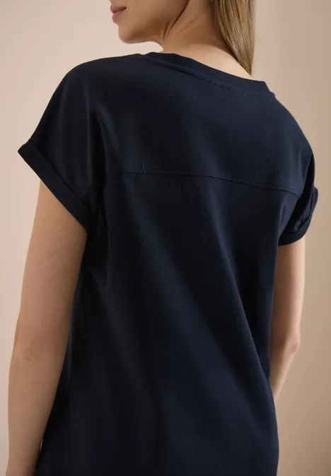Een vrouw met de rug naar de camera draagt een donkerblauw T-shirt.