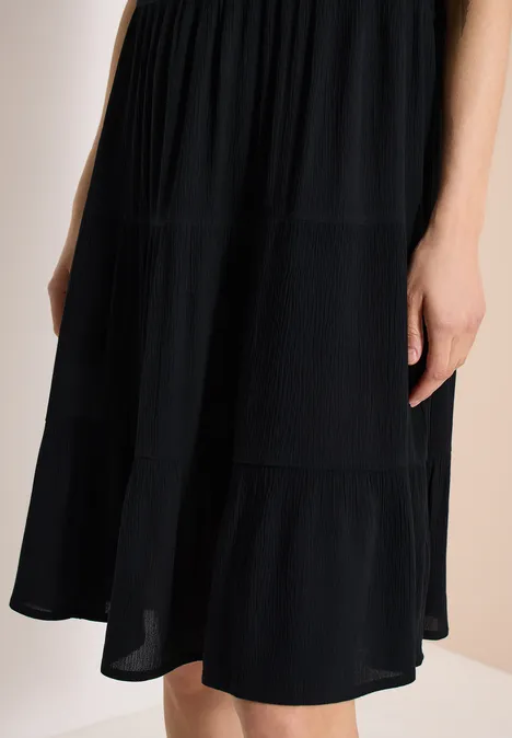 Zwarte midi-jurk met lagen van lichtgewicht stof.