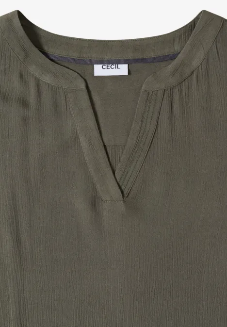 Olivengroene blouse met V-hals, fijne ribstructuur, subtiele verticale plooitjes en 'CECIL'-label in de kraag.