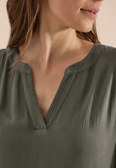 Detail van een donkergrijs, gestructureerd V-hals damestopje.