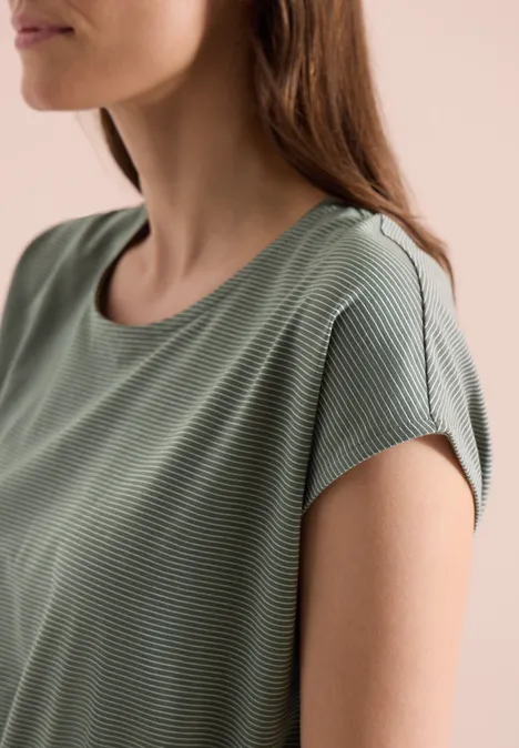 Close-up van een vrouw van schouder tot kin in een groen T-shirt met fijne streepjes.