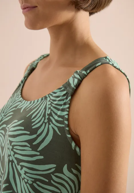 Donkergroen dames-top met lichtgroene bladprint en diepe ronde hals, sportief-chique uitstraling.