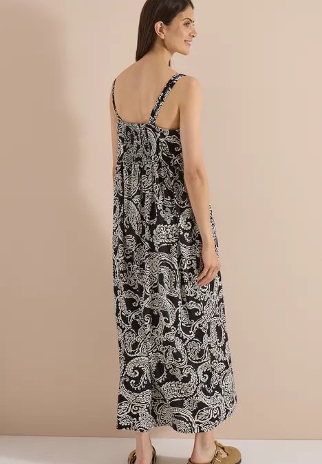 Eine Frau von hinten in langem schwarz-weißem Paisley-Kleid mit Spaghettiträgern.