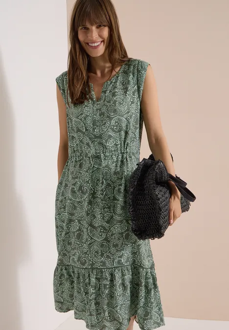 Midikleid mit Split Neck und Print khaki Frau trägt ärmelloses, grünes Maxikleid mit Blumenmuster und Taillengürtel, hält eine runde Strohtasche.
