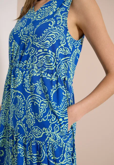 Midikleid mit V-Neck und Print surf blue Eine Frau in einem ärmellosen, knielangen, blau-grünen Kleid mit Paisley-Muster, Hand in Tasche, seitliche Ansicht.