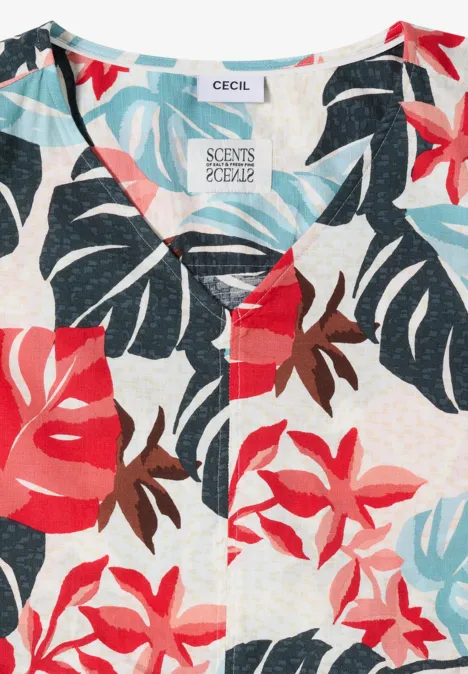 Blouse légère à motif tropical de feuilles et fleurs rouges, bleues et turquoises sur fond clair.