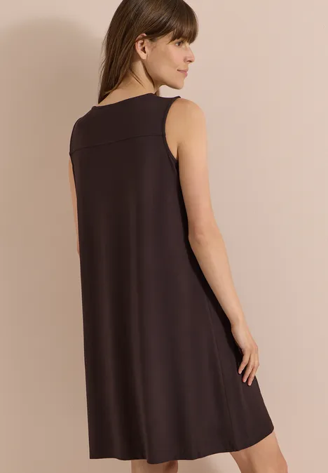 Knielanges Jerseykleid mit V-Neck brown cacao Junge Frau von hinten in ärmellosem, locker fallendem, dunkelbraunem A-Linien-Kleid vor hellem Hintergrund.