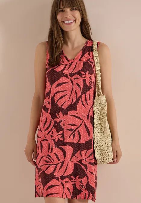 Knielanges Jerseykleid mit V-Neckund Print coral Frau trägt ärmelloses, tropisch gemustertes Rot-Schwarz-Kleid mit Basttasche.