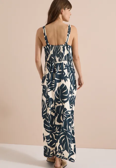 Maxikleid mit V-Neck und Print palm breeze green Frau von hinten in ärmellosem Maxikleid mit blauem Blattmuster vor hellem Hintergrund.