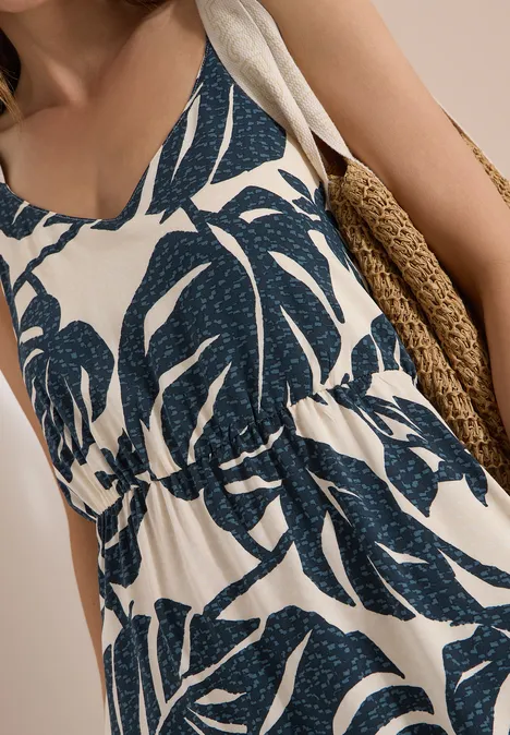 Maxikleid mit V-Neck und Print palm breeze green Ärmelloses Kleid mit blauem Blattmuster und lockerer Passform, dazu ein geflochtenes Strohtäschchen.