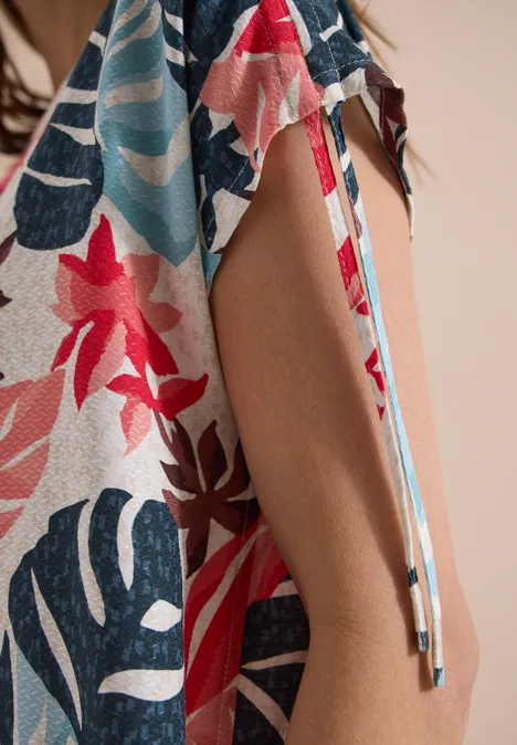 Robe mi-longue avec manchons light alabaster white Gros plan sur un tissu léger à motifs floraux et feuillages colorés, fente latérale avec lien à nouer.