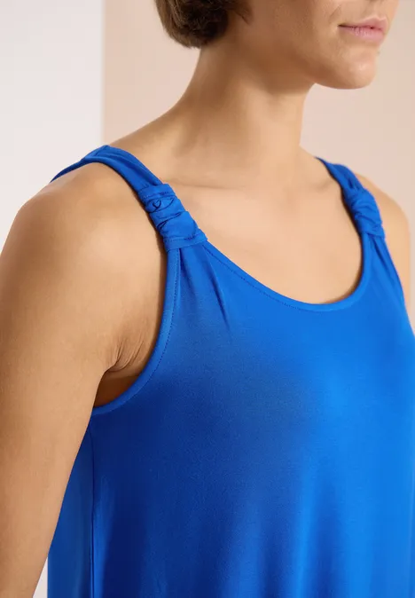 Knielanges Kleid mit Knotendetail surf blue Frau in blauem ärmellosem Top mit gerafften Trägern, Nahaufnahme von Oberkörper und Schultern.