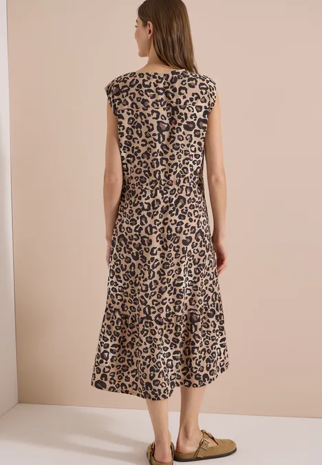 Midi-Kleid mit Split Neck und Leo-Print urban taupe Frau von hinten in ärmellosem, midilangen Leopardenkleid und flachen Ballerinas vor beigem Hintergrund.
