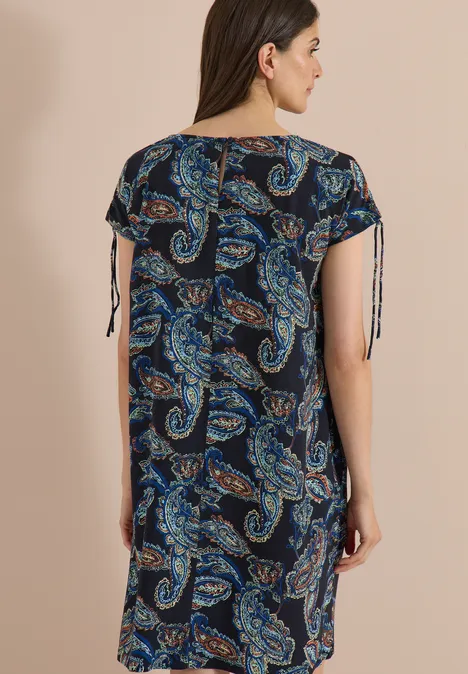 Robe mi-longue à manches courtes universal blue Femme vue de dos, portant une robe ample mi-longue à motif cachemire bleu et manches à liens.