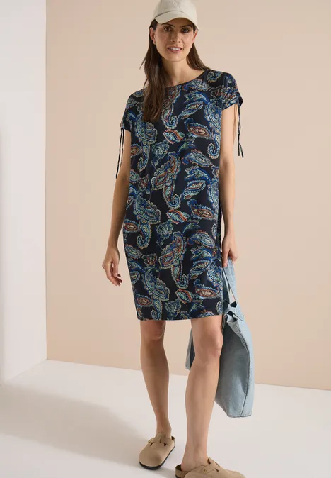 Robe mi-longue à manches courtes universal blue Femme en robe courte imprimé cachemire à col V, casquette, sandales, tenant une veste en jean.