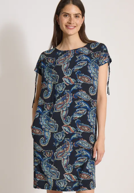 Robe mi-longue à manches courtes universal blue Femme portant une robe bleu marine à motifs cachemire, manches courtes et liens latéraux.