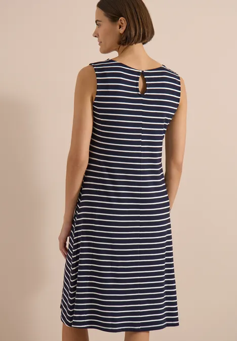 Femme de dos portant une robe midi sans manches rayée bleu marine et blanc avec découpe au dos.