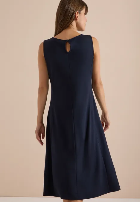 Midi-jurk met ronde hals van jersey urban dark blue Vrouw van achter gefotografeerd in een donkerblauwe mouwloze midijurk met klein rugdetail en uitlopende rok.