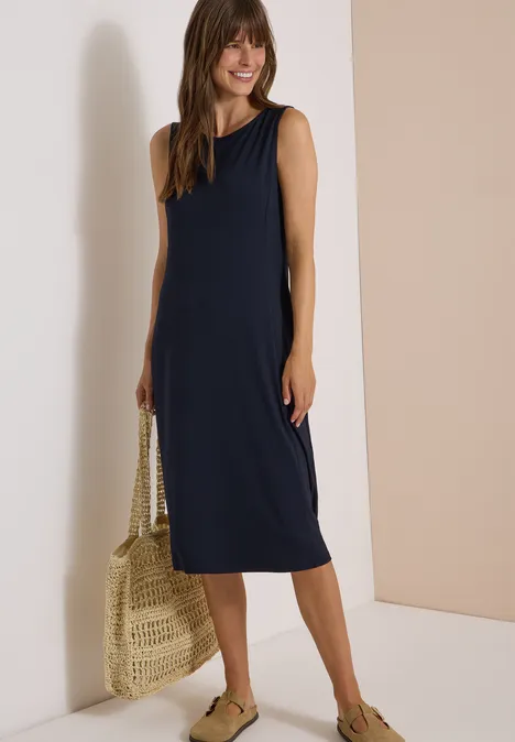 Midi-jurk met ronde hals van jersey urban dark blue Vrouw in donkerblauwe mouwloze midijurk, strozak en groene espadrilles.
