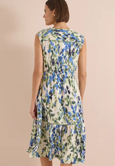 Midikleid mit Split Neck und Print cashmere beige Frau von hinten in ärmellosem, blau-grün gemustertem Midikleid vor neutralem Hintergrund.