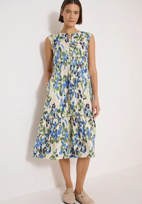 Midikleid mit Split Neck und Print cashmere beige Frau steht vor weißem Hintergrund, trägt ärmelloses Midikleid mit grün-blauem Blumenmuster und Stufenrock.
