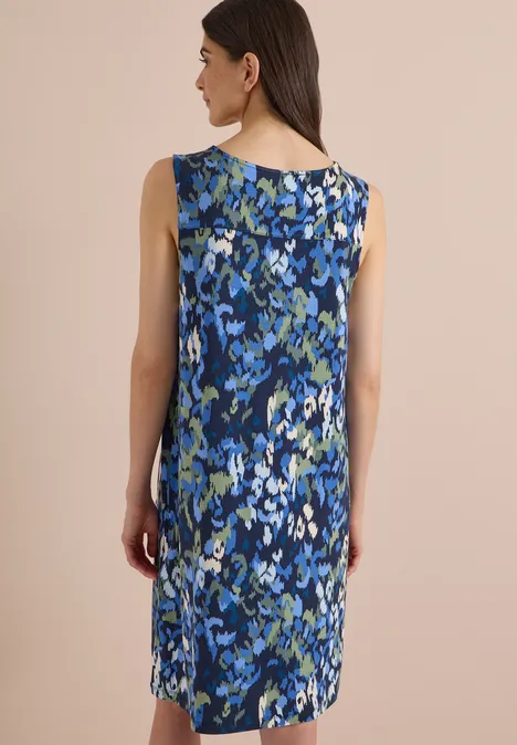 Frau von hinten in ärmellosem, knielangem Kleid mit blauem Blumenmuster.