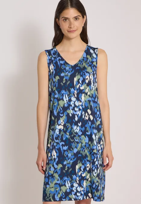 Eine Frau trägt ein ärmelloses, knielanges A-Linien-Kleid mit blau-grünem abstraktem Blumenmuster.