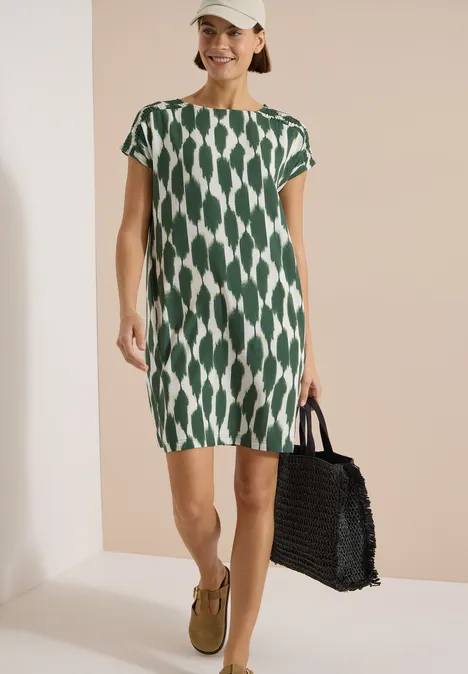 Knielanges Kleid mit Capsleeves und Print vanilla white Frau trägt kurzärmeliges, grün-weiß gemustertes Kleid und hält eine schwarze Flechtkorb-Tasche.