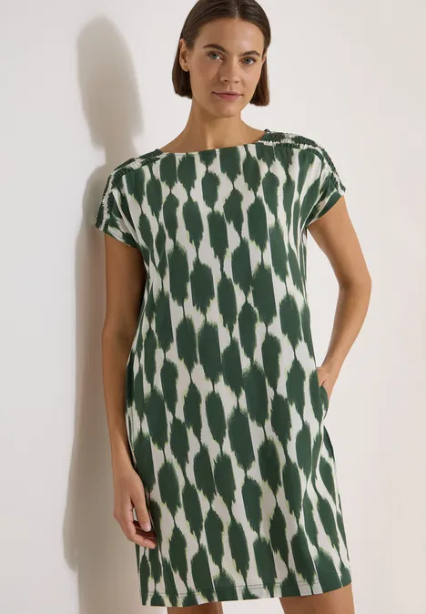 Knielanges Kleid mit Capsleeves und Print vanilla white Frau in einem grünen, weiß gemusterten Etuikleid mit kurzen Ärmeln.