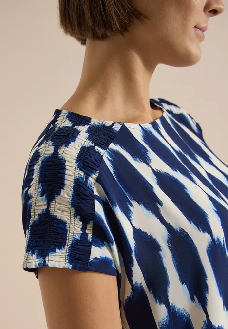 Knielanges Kleid mit Capsleeves und Print urban dark blue Frau in blau-weiß gemustertem Kurzarmshirt, Nahaufnahme von Schulter und Profilansicht.