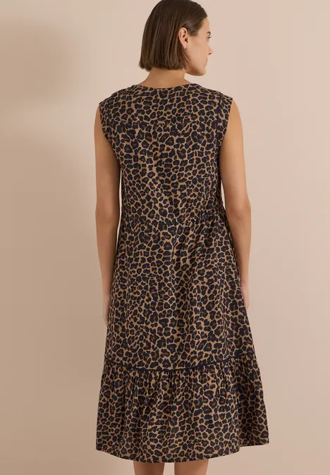 Eine Frau von hinten im ärmellosen Midikleid mit Leopardenmuster.